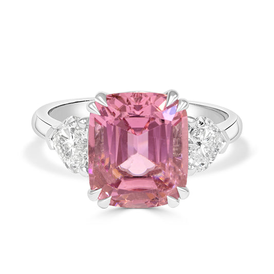 Ring with a pink tourmailine and heart shape diamond trilogy band on a white background